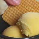 Dos bolas de helado de fruta de la pasión en una tarrina con una galleta